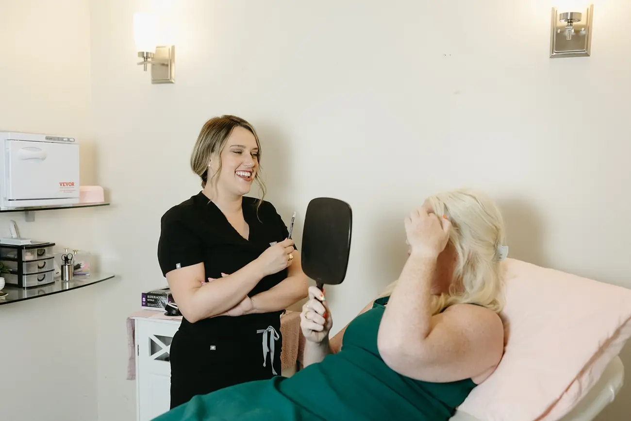 Marley holding up a hand mirror for a client in the treatment room